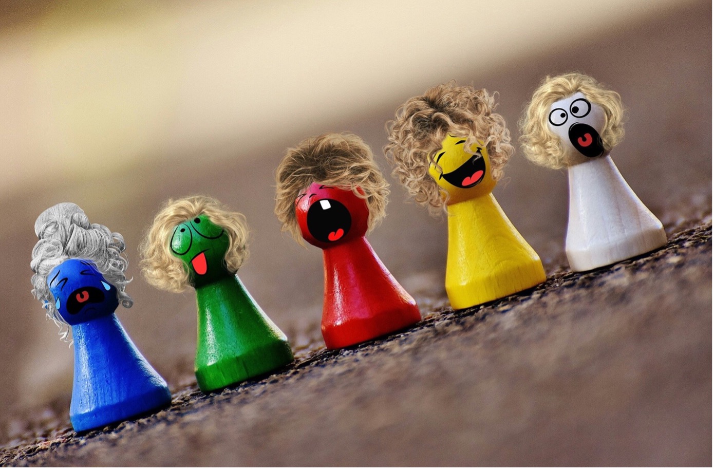 5 Holzfiguren mit Gesicht und Frisur, jede Figur drückt eine andere Emotion aus