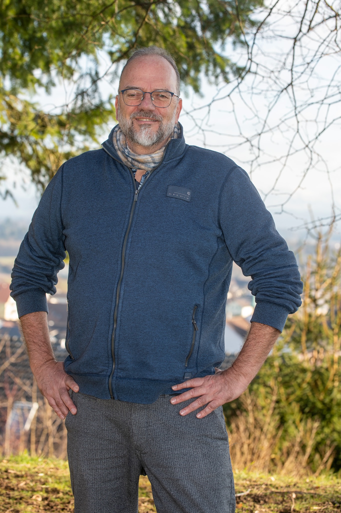 Urs-Micheal Hoenner steht lachend in der Natur und stützt die Arme in der Hüfte ein